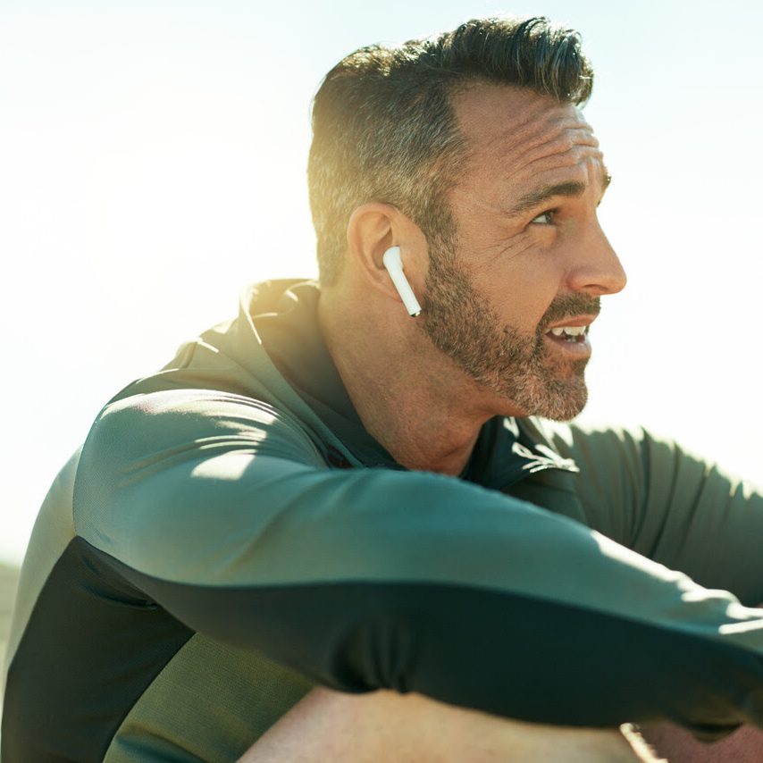 Shot of a mature man using wireless earphones while out for his workout